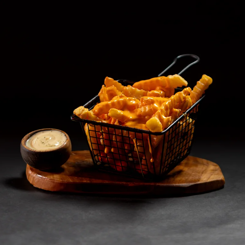 Frites nappées de cheddar, photographiées dans leur panier